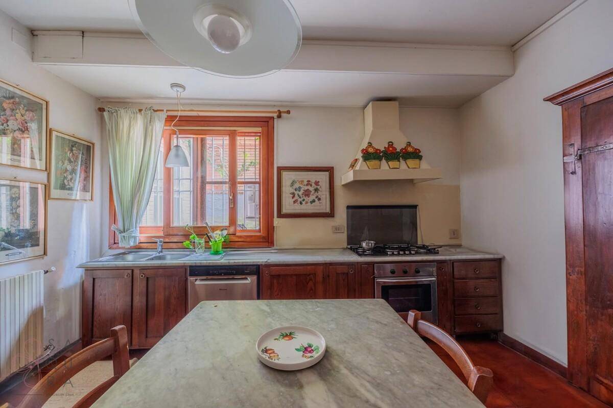 Traditionelle Küche mit Holzeinbauten, Gasherd und einem Fenster, das viel Licht hereinlässt.