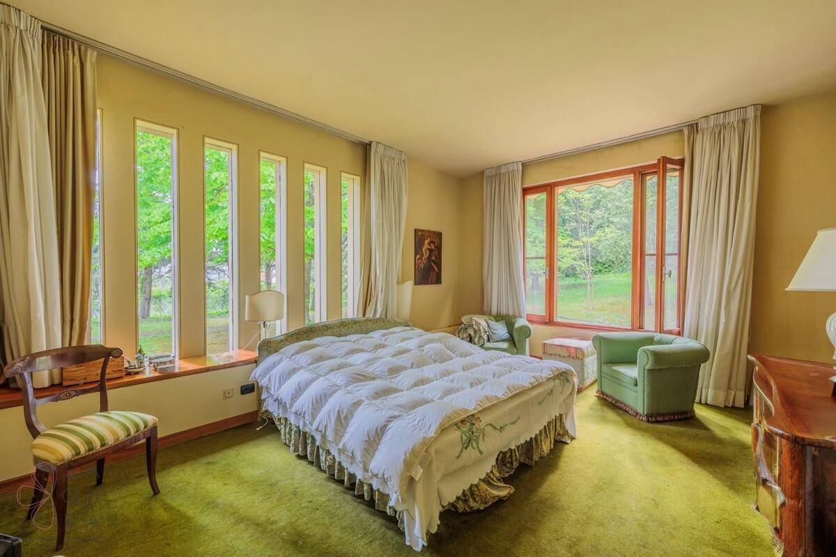 Schlafzimmer mit grünem Teppichboden, großen Fenstern und viel Tageslicht, gemütlich eingerichtet.