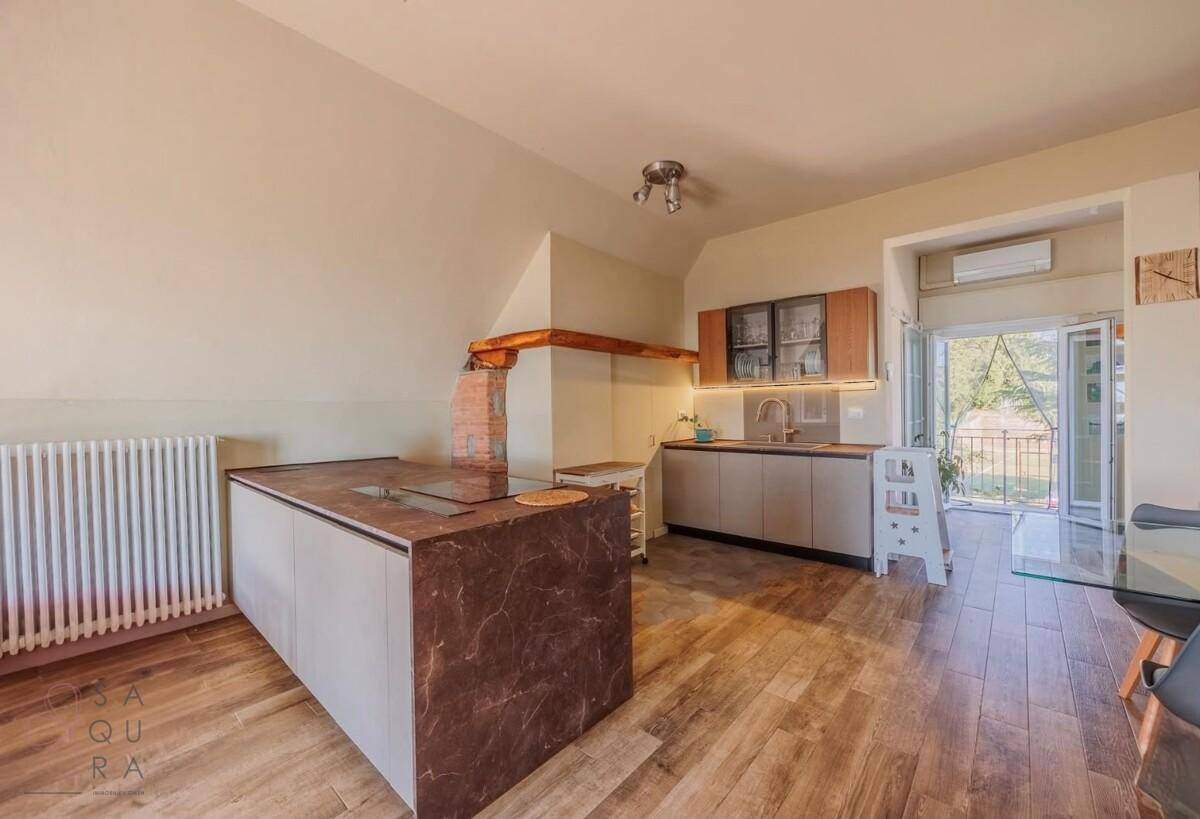Moderne Küche mit Kücheninsel, Holzboden und Zugang zu einem Außenbereich.