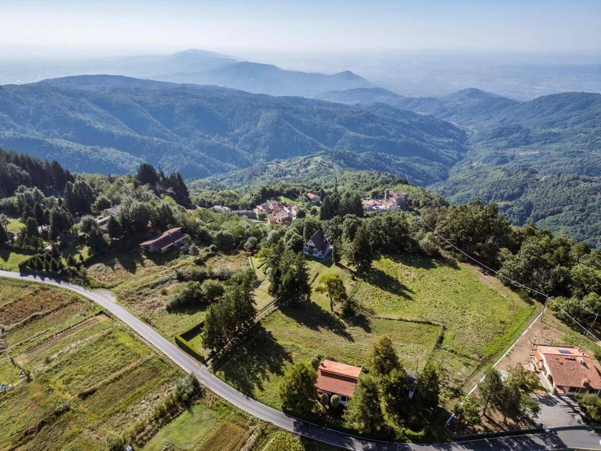 Weitläufige Berglandschaft mit verstreuten Häusern und einem Dorf in der Ferne.