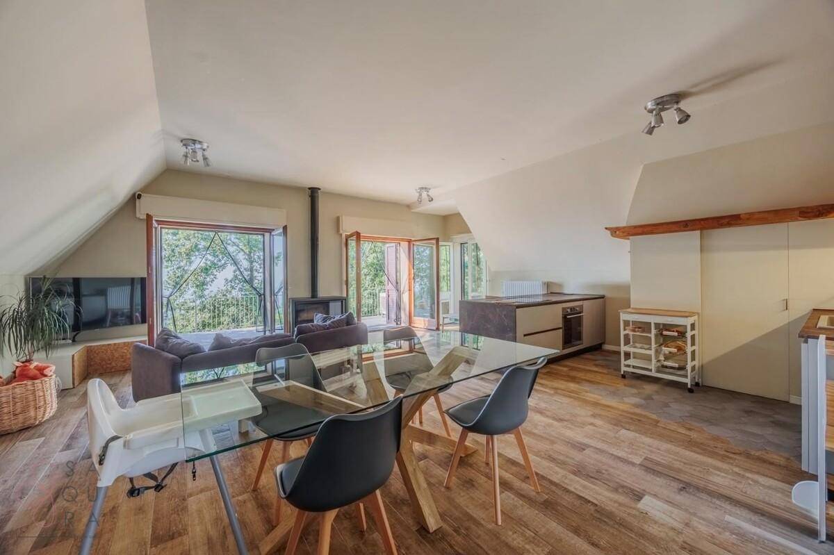 Heller offener Wohn-Essbereich mit Holzboden, Kamin und Zugang zum Balkon.