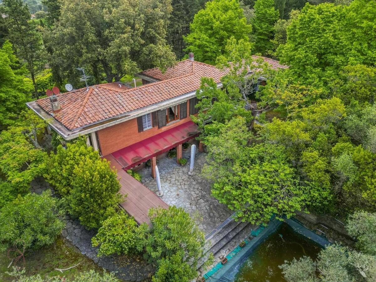 Vogelperspektive des Hauses mit rotem Ziegeldach, umgeben von Bäumen und einem Poolbereich.