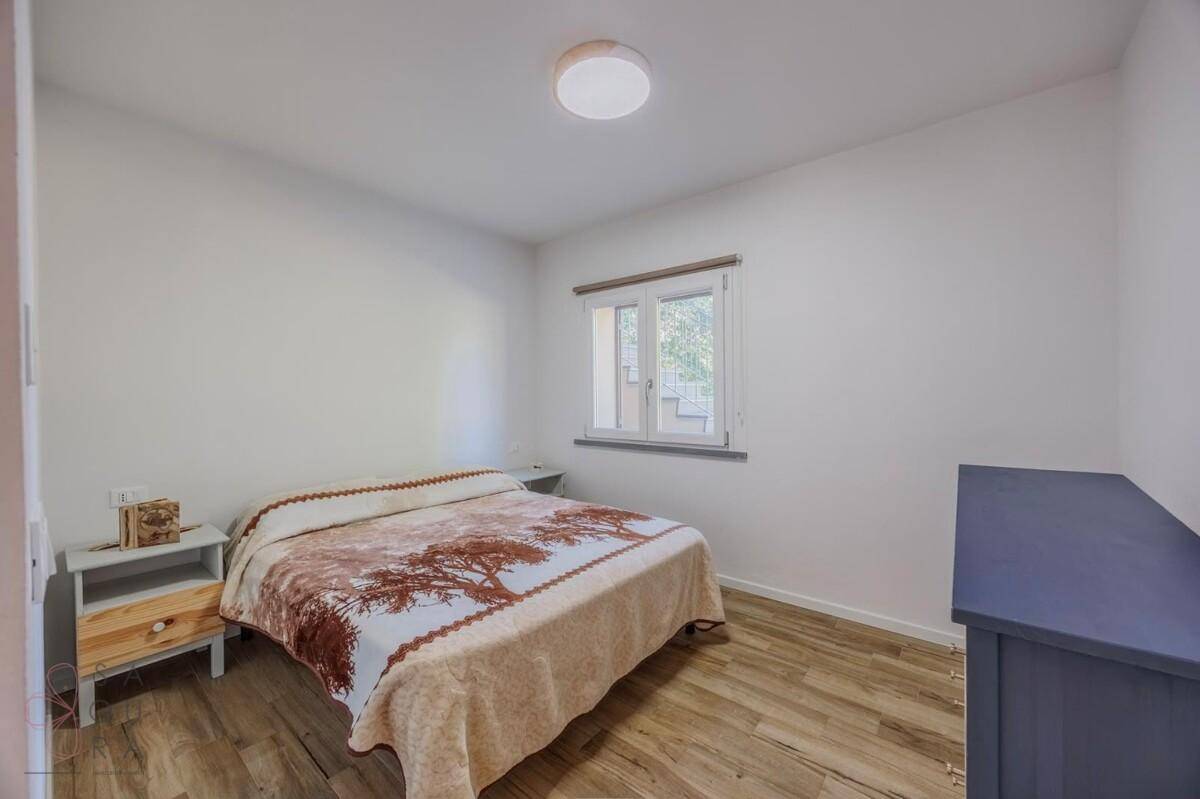 Gemütliches Schlafzimmer mit Holzboden, Doppelbett und Fenster mit Blick ins Grüne.
