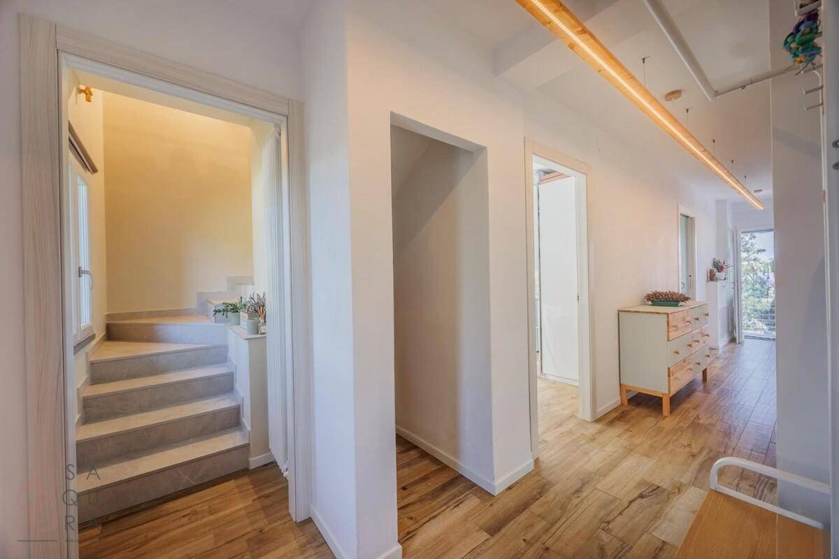 Heller Flur mit Holzboden, weiß gestrichenen Wänden und Treppenaufgang.