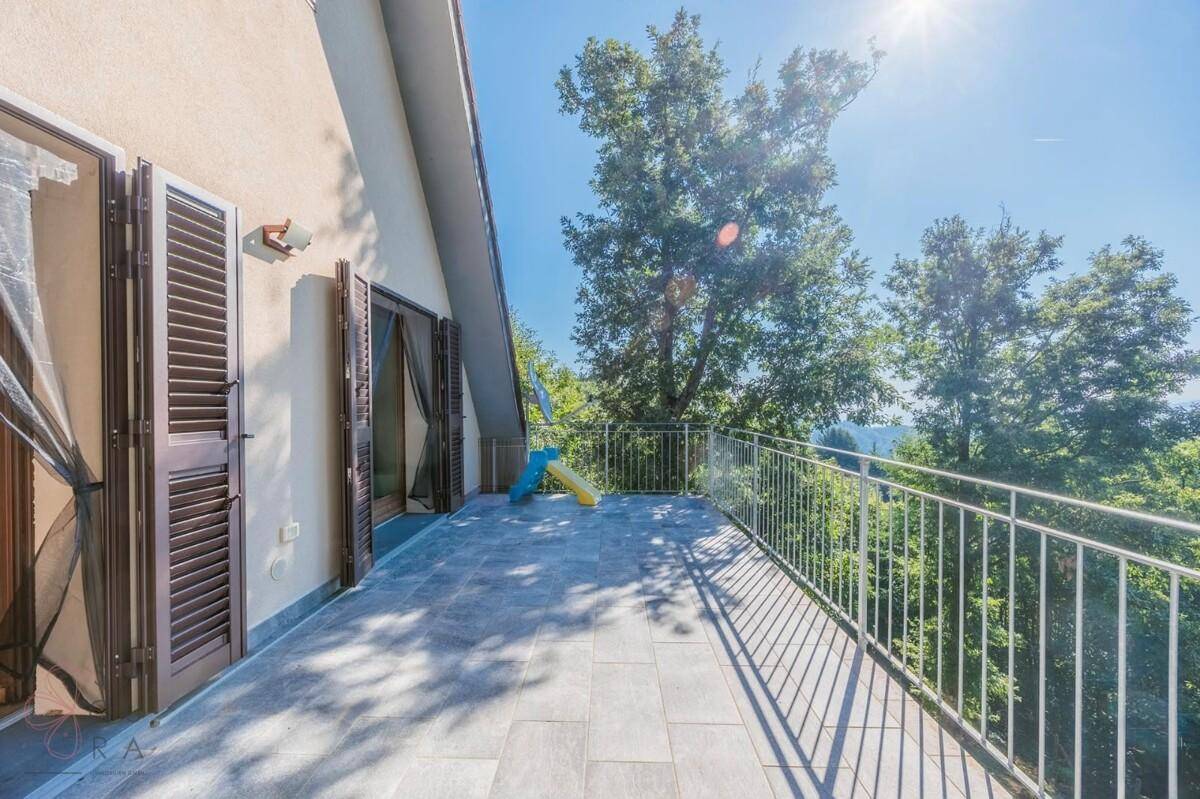 Sonniger Balkon mit Metallgeländer und weitem Blick über die Baumwipfel.