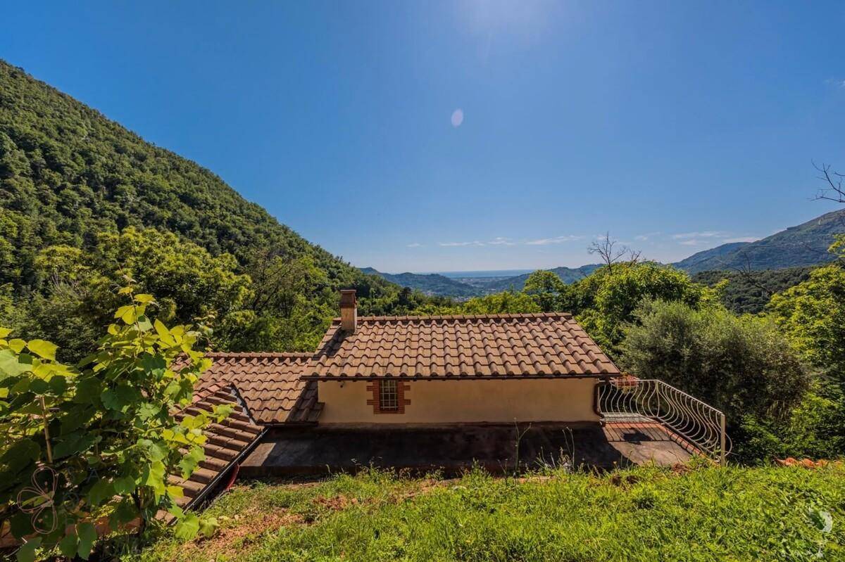 Rückansicht des Hauses mit Ziegeldach und weitem Blick über die grüne Landschaft bis zum Horizont.