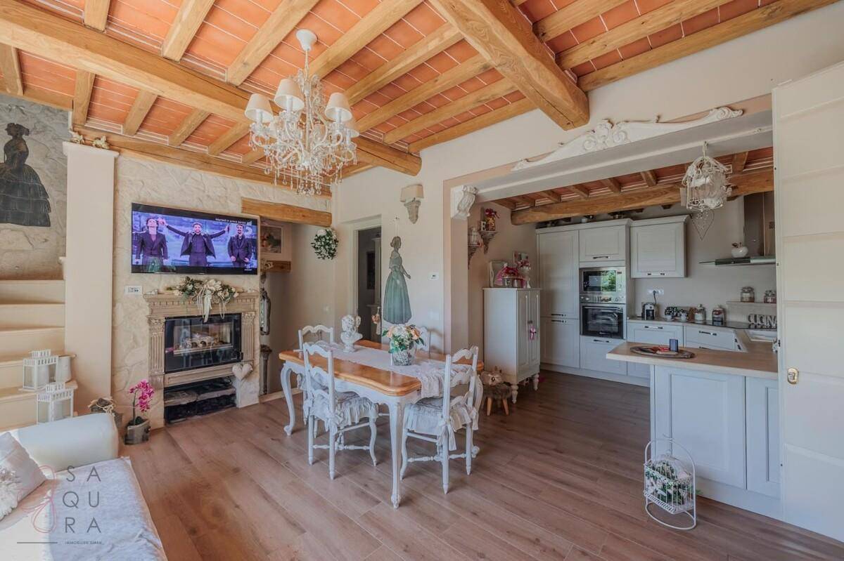 Offener Wohn-Essbereich mit integrierter Küche, Holzbalkendecke und traditionellem Kamin.