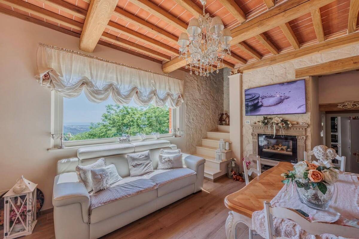 Gemütlicher Wohn-Essbereich mit Holzbalkendecke, Kamin und großem Fenster mit Panoramablick.