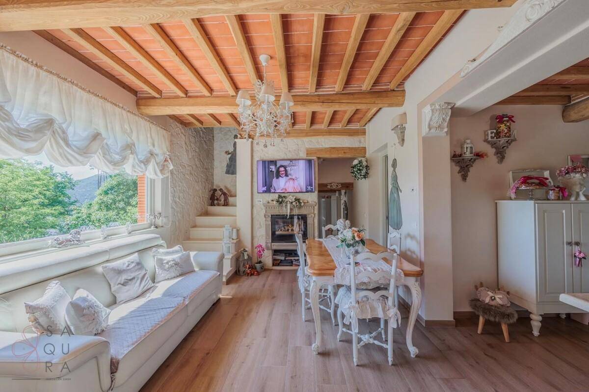 Heller Wohn- und Essbereich mit Holzbalkendecke, eleganten Möbeln und Blick ins Grüne.