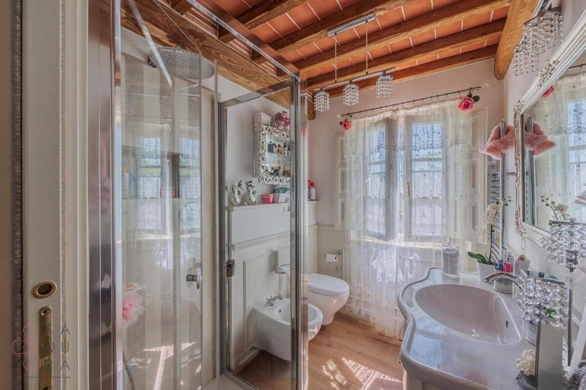Helles Badezimmer mit Dusche, Bidet, Einzelwaschbecken und Fenster.