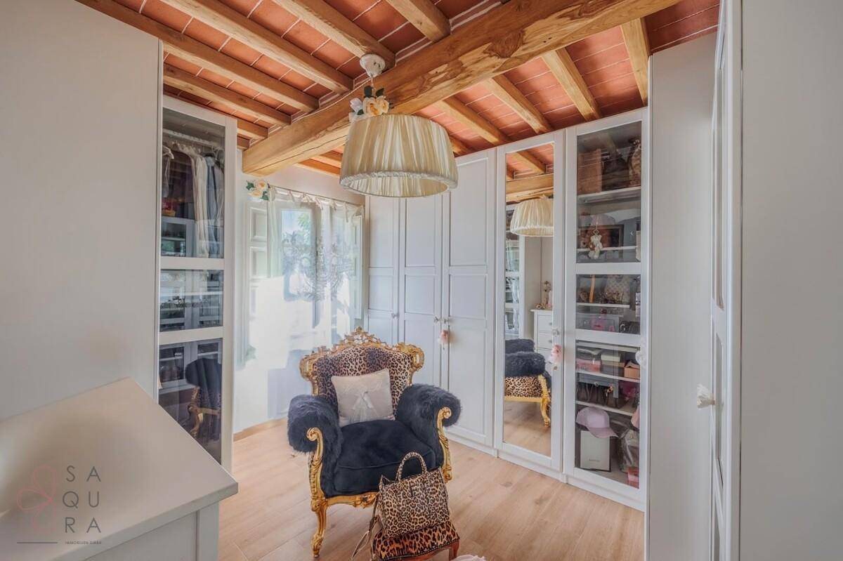 Elegantes Ankleidezimmer mit Spiegelschränken, Sitzgelegenheit und Holzbalkendecke.