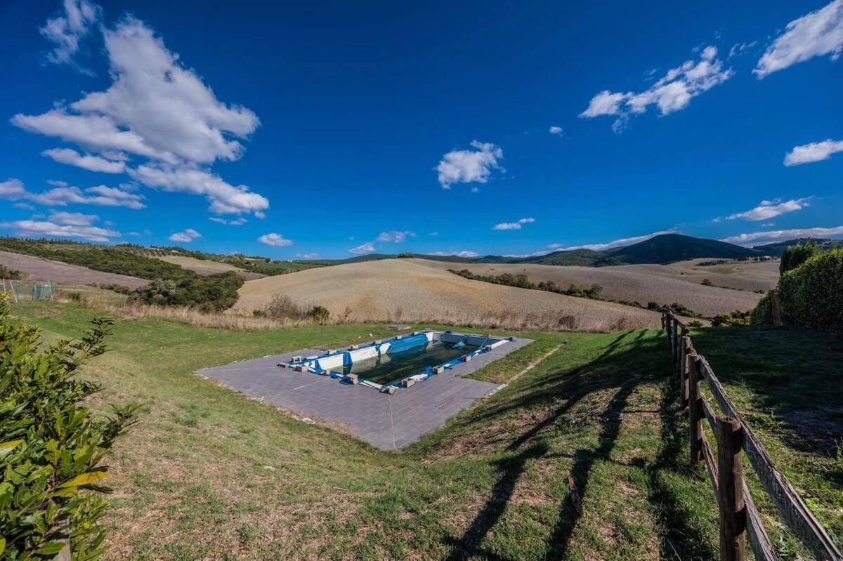 Außenpool mit Blick auf die weite, hügelige Landschaft unter einem klaren blauen Himmel.