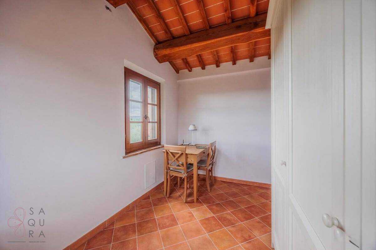 Helles Schlafzimmer mit Terrakottaboden, Holzbalkendecke und integriertem Kleiderschrank.