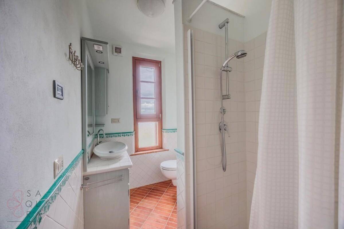Modernisiertes Badezimmer mit Dusche, Terrakottaboden und schlichter Waschtischplatte.
