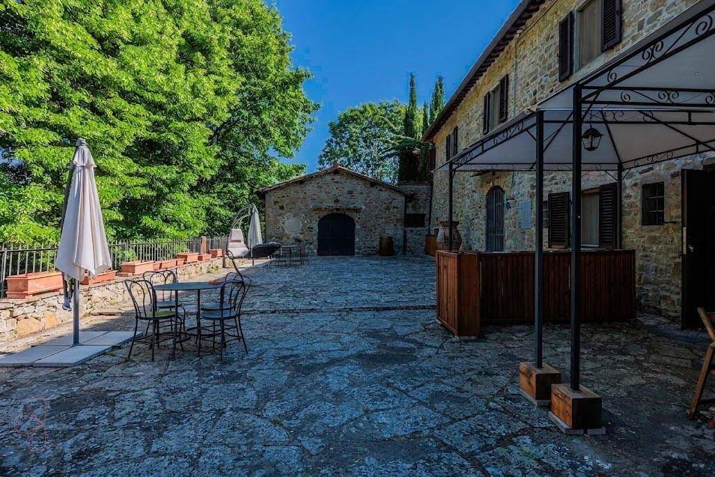 Geräumiger gepflasterter Innenhof mit Gartenmöbeln und Sonnenschirm, ideal für entspannte Stunden im Freien.