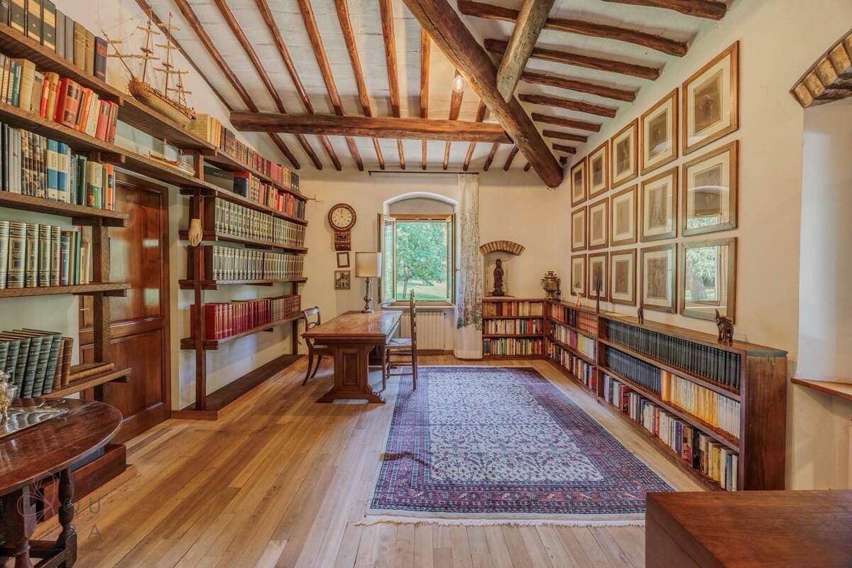 Geräumiges Arbeitszimmer mit Holzboden, Bücherregalen und einem großen Schreibtisch mit Blick ins Grüne.