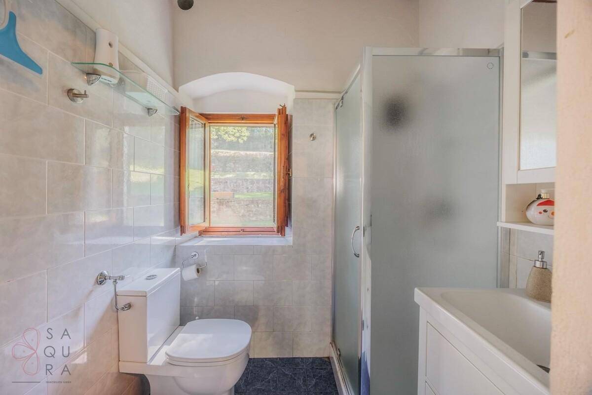 Helles Badezimmer mit Dusche, WC und Fenster.