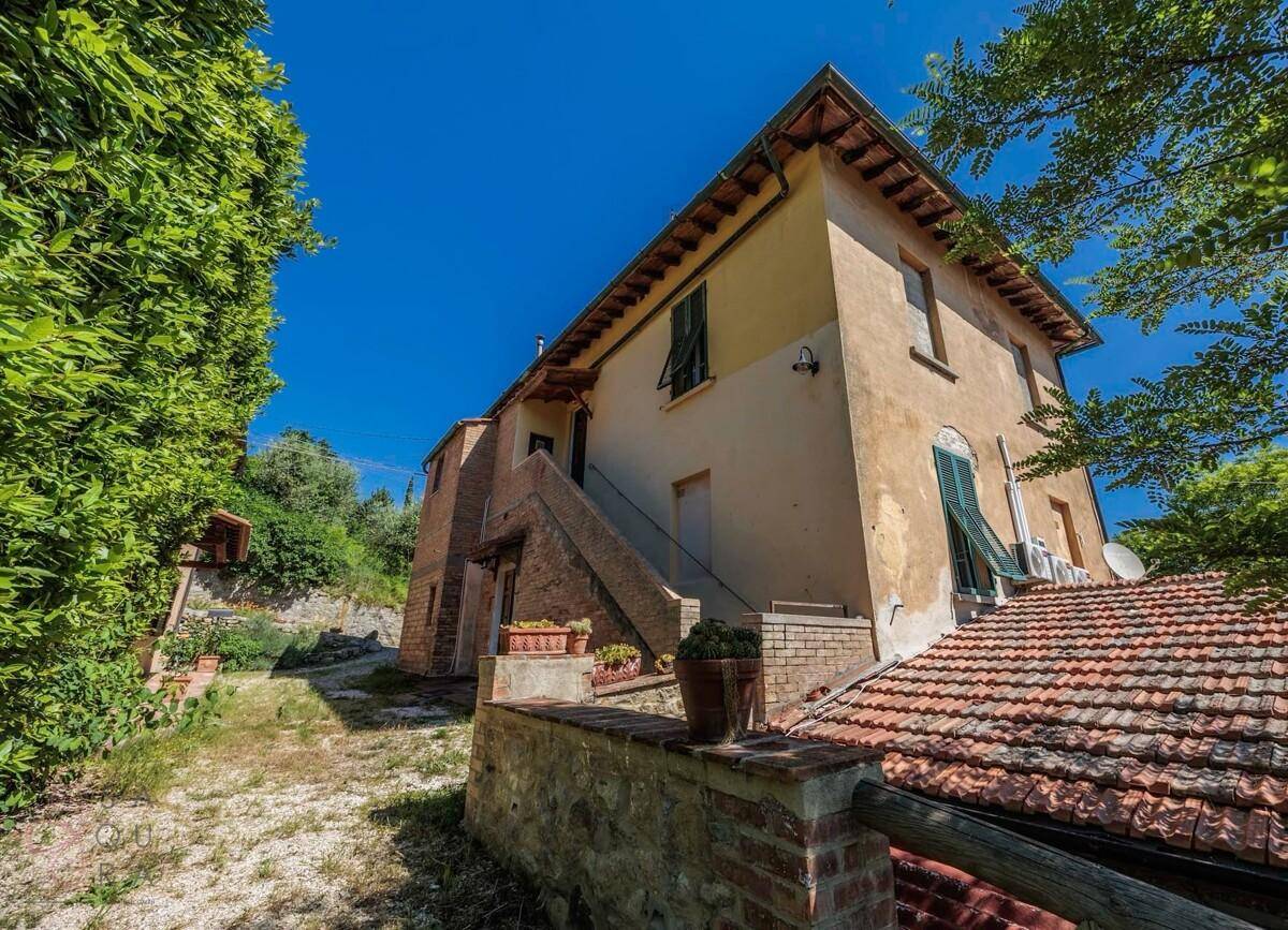 Seitenansicht des Landhauses mit Außentreppe und traditionellem Ziegeldach.
