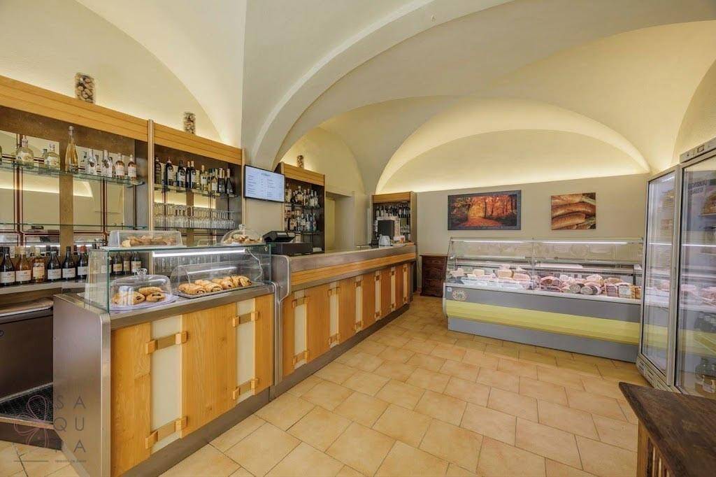 Moderne Bar mit gewölbter Decke, Vitrinen und einer Auswahl an Getränken und Speisen.