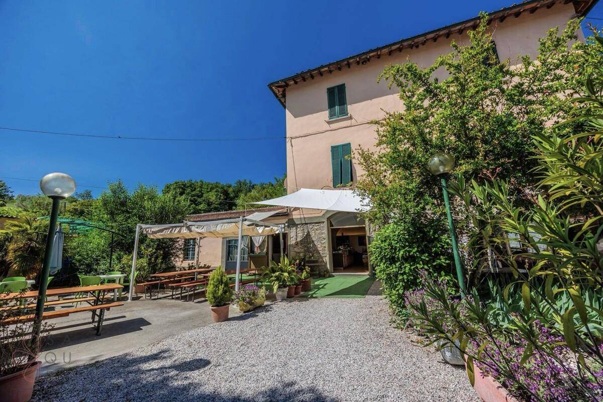 Eingangsbereich mit überdachter Terrasse und rustikalen Biertischgarnituren im Freien.