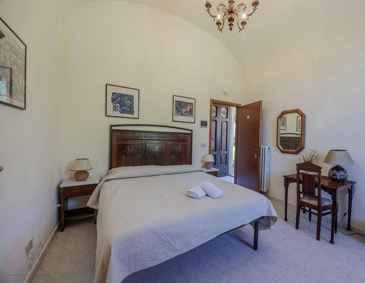 Schlafzimmer mit gewölbter Decke, Doppelbett und traditionellen Nachttischen.