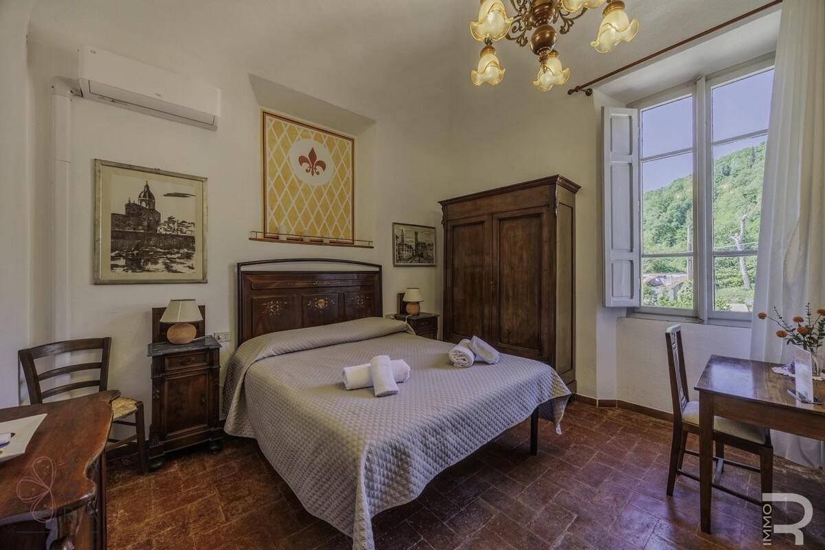 Helles Schlafzimmer mit Terrakottaboden, antiken Möbeln und Blick ins Grüne.