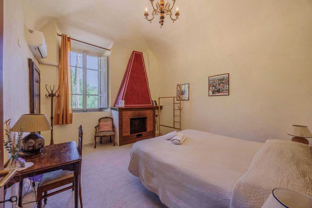 Geräumiges Schlafzimmer mit Kamin, Terrakottaboden und traditioneller Einrichtung.