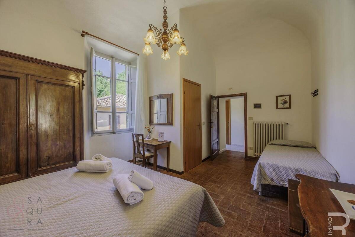 Gemütliches Schlafzimmer mit Terrakottaboden, Holzbett und traditionellem Kronleuchter.