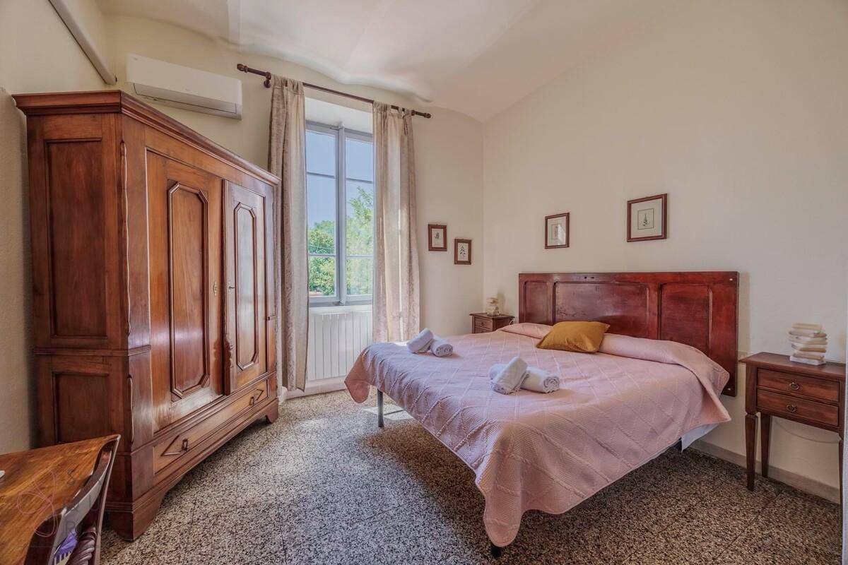 Schlafzimmer mit großem Holzschrank, Doppelbett und Terrazzoboden.