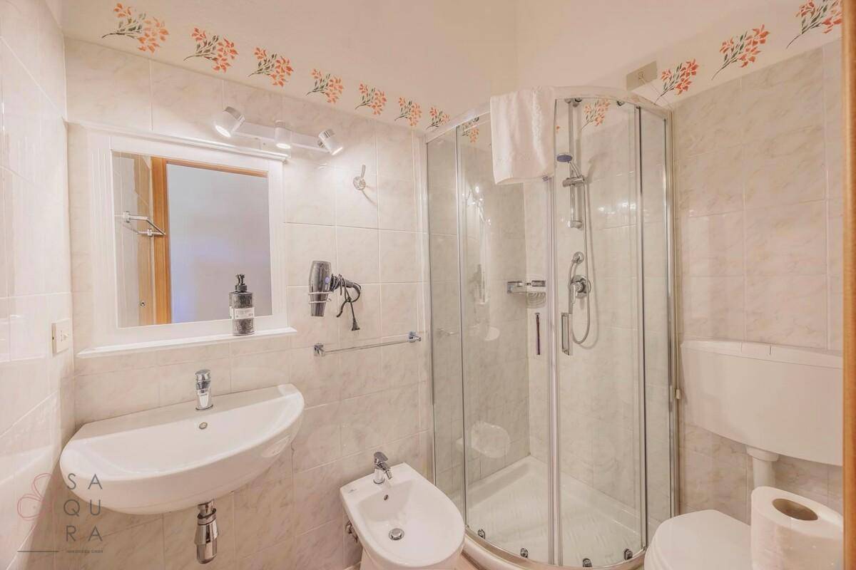 Modernes Badezimmer mit Duschkabine, Bidet und Waschbecken mit Spiegel.