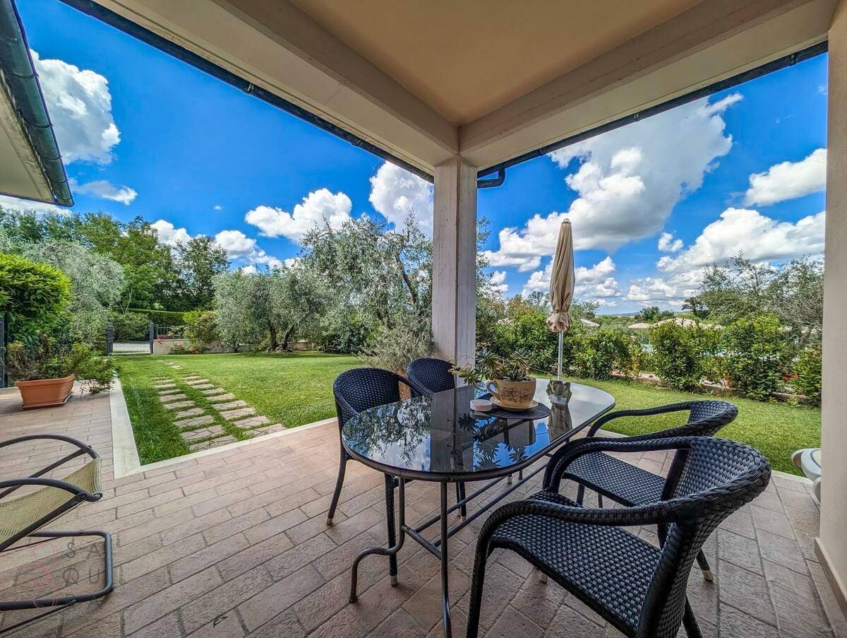 Überdachte Terrasse mit Gartenmöbeln und Blick auf den Rasen und die umliegende Natur.