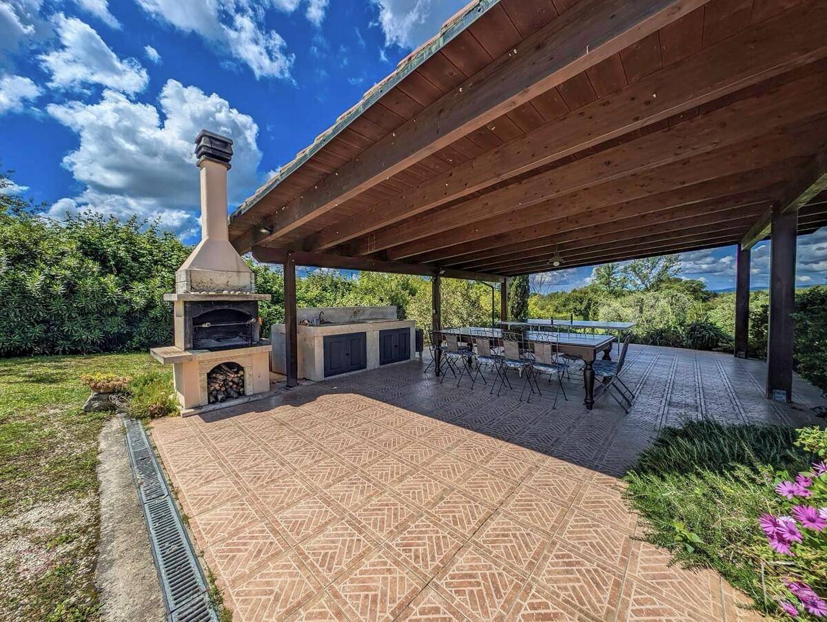Überdachte Terrasse mit großem Grillbereich, Außenküche und Esstisch für gesellige Runden.