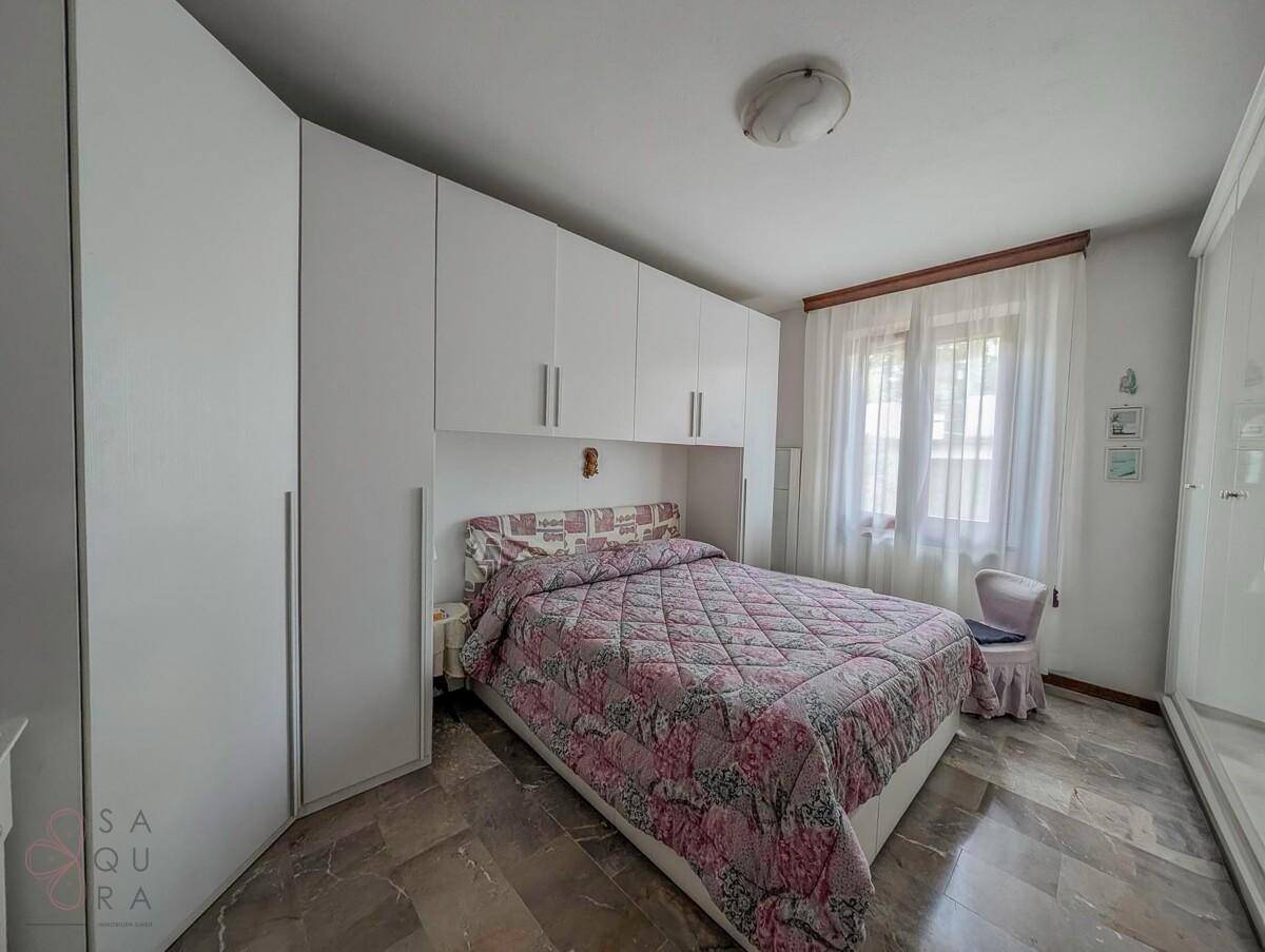 Schlafzimmer mit weißen Einbauschränken, Doppelbett und elegantem Marmorboden.