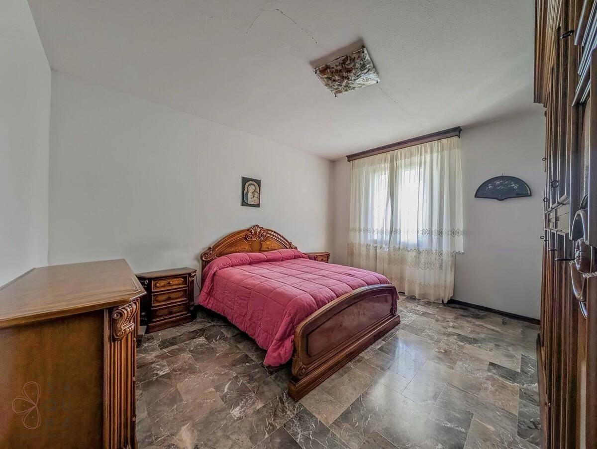 Schlafzimmer mit traditionellem Holzbett und Kommode, ergänzt durch Marmorboden.