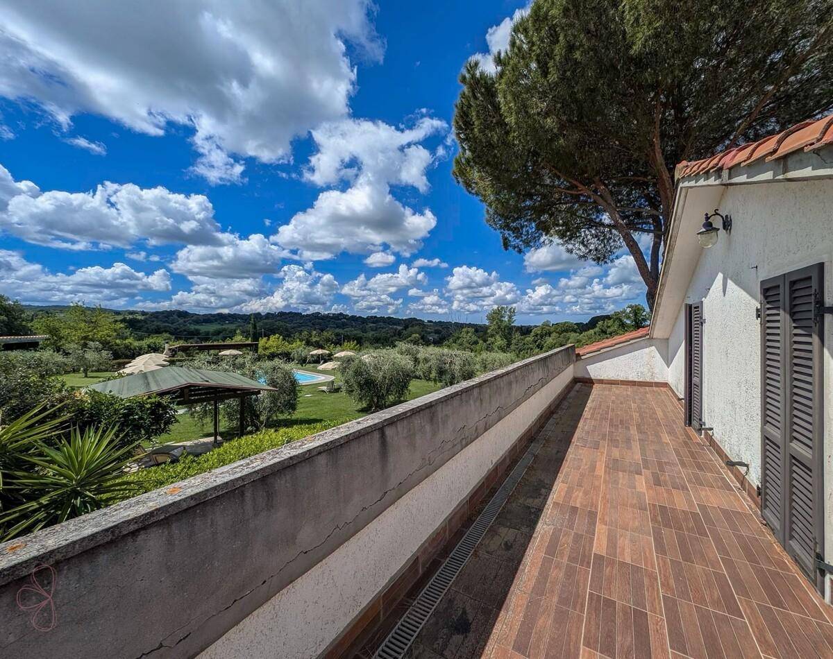 Langer Balkon mit Fliesenboden und weitem Blick auf die Landschaft und den Poolbereich.