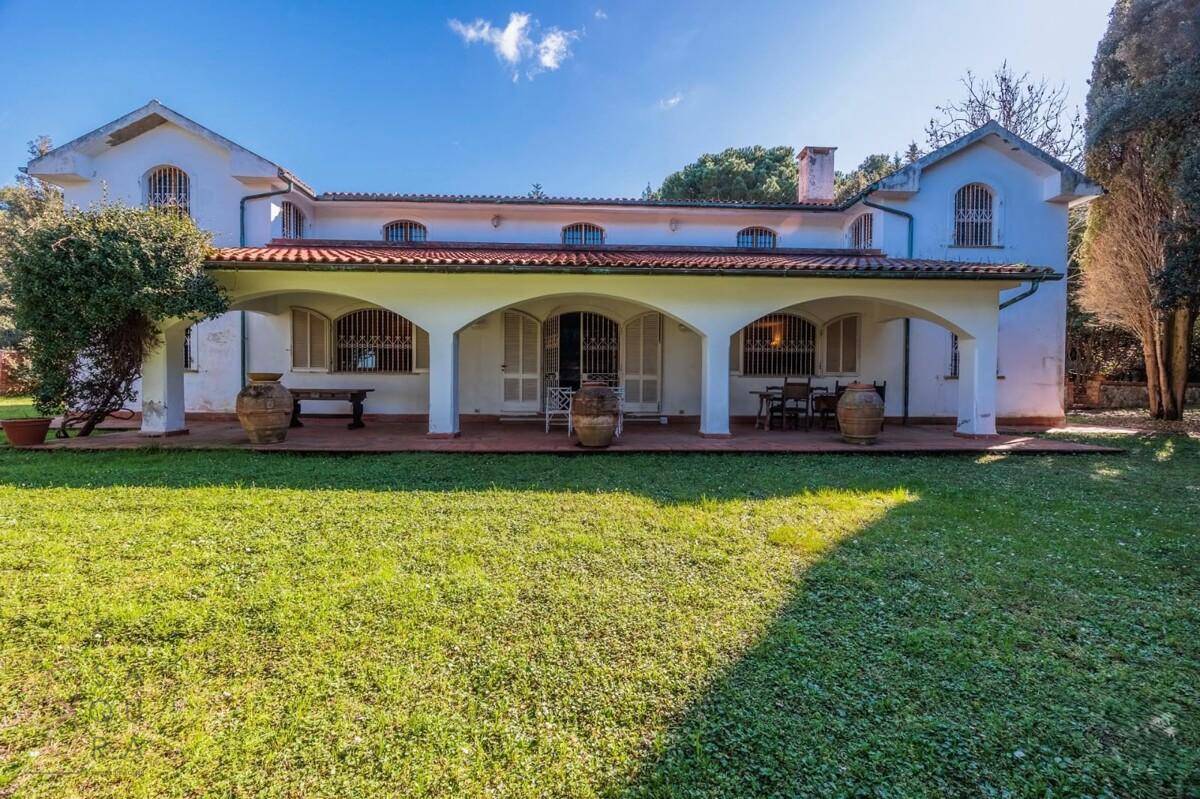 Frontansicht des Hauses mit weitläufigem Rasen und einer einladenden, überdachten Loggia.
