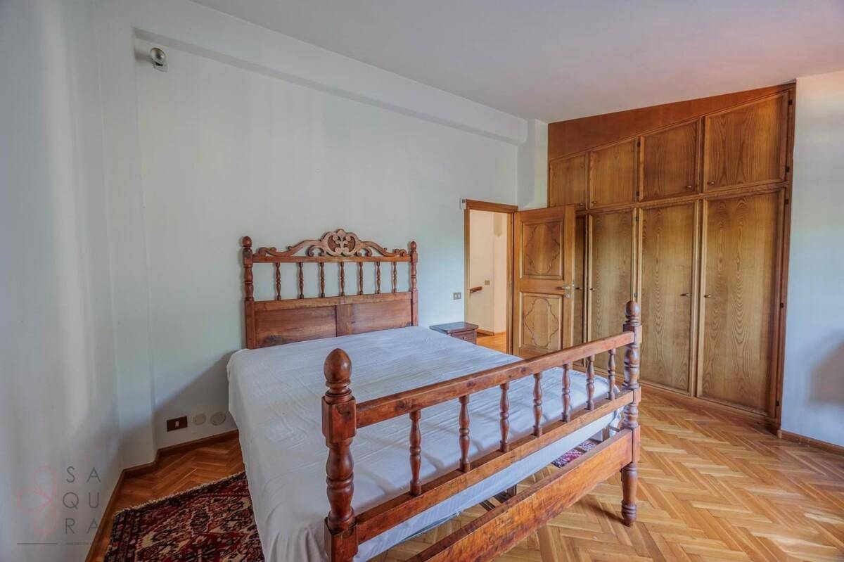 Schlafzimmer mit Holzbett, Einbauschränken und Fischgrätparkettboden.