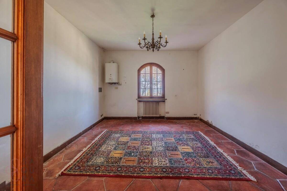 Leerer Raum mit Terrakottaboden, Heizkörper und einem Bogenfenster.