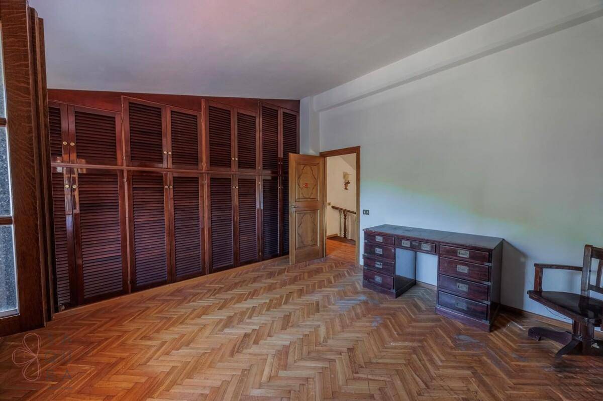 Arbeitszimmer mit Parkettboden, großer Einbauschrankwand und klassischem Holzschreibtisch.