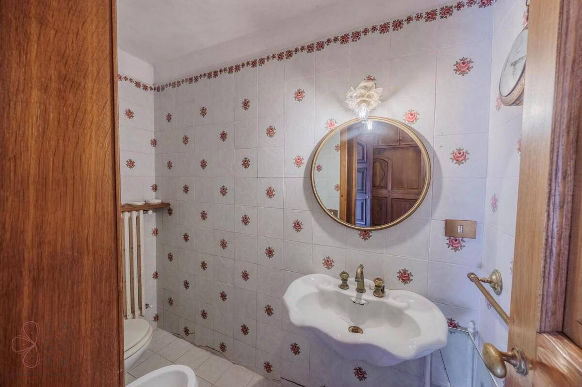 Badezimmer mit gemusterten Fliesen, Einzelwaschbecken, Toilette und Bidet.