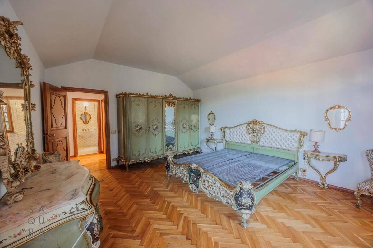Prunkvolles Schlafzimmer mit verziertem Bett, passendem Kleiderschrank und Fischgrätparkett.