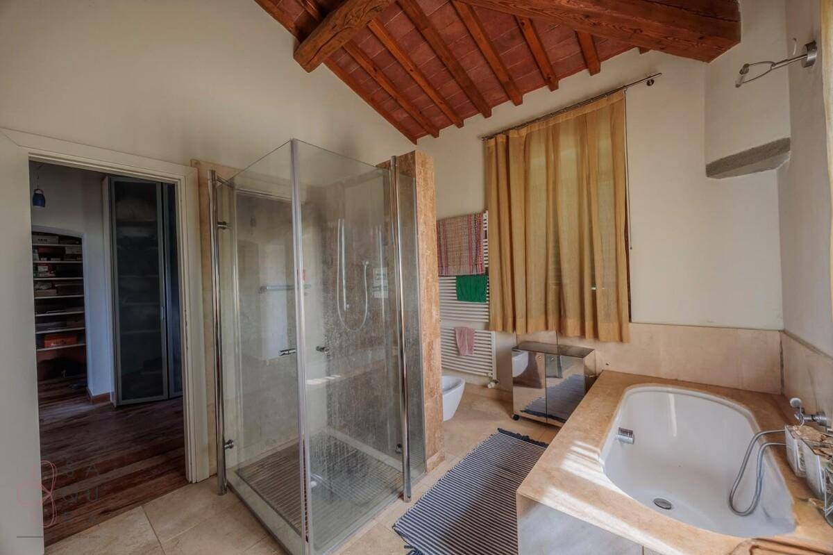 Geräumiges Badezimmer mit Badewanne, Dusche und Holzbalkendecke, hell und funktional eingerichtet.