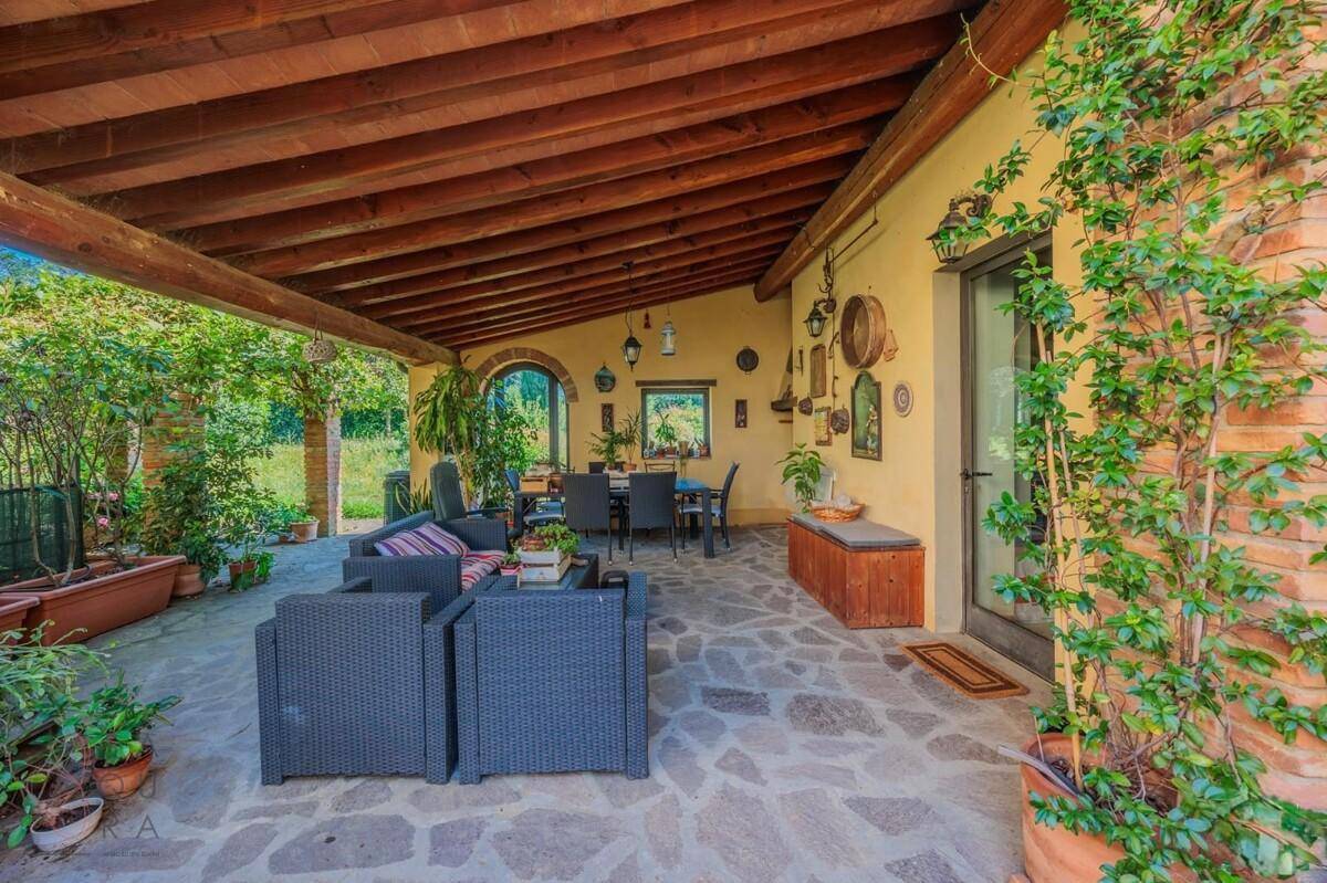 Gemütliche überdachte Terrasse mit Sitzgelegenheiten und Blick ins Grüne, ideal für Entspannung im Freien.