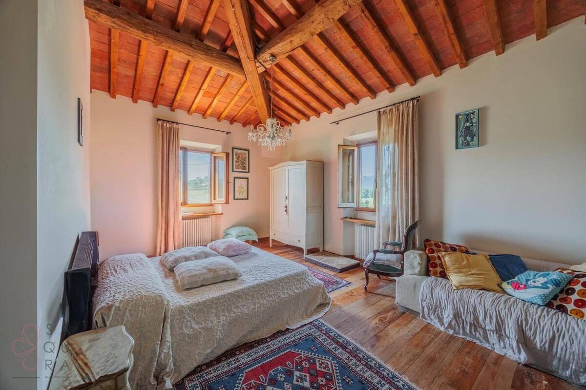 Geräumiges Schlafzimmer mit Holzboden, Holzbalkendecke und Sofa, hell und einladend gestaltet.