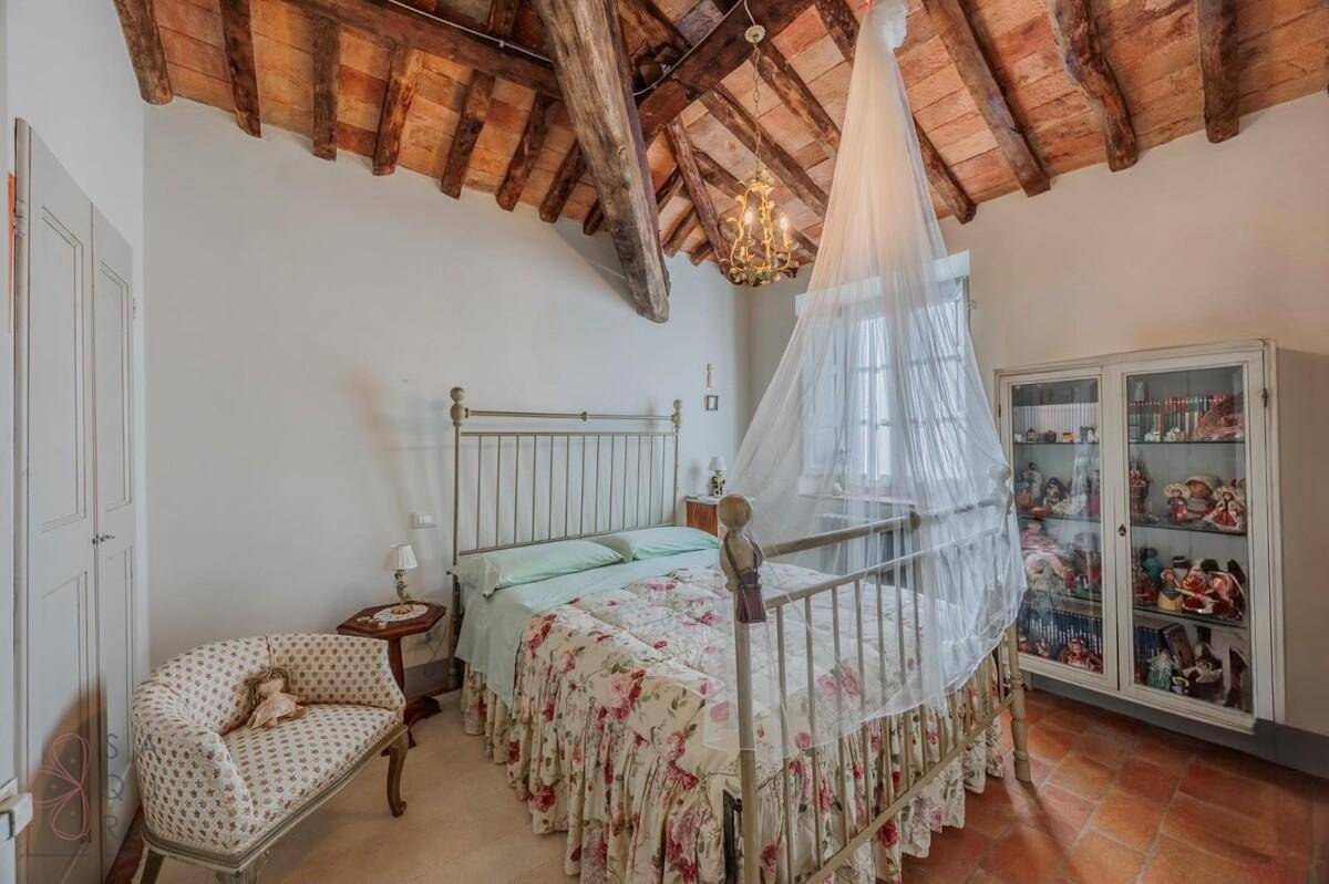 Gemütliches Schlafzimmer mit Himmelbett, sichtbaren Holzbalken und traditionellem Terrakottaboden.