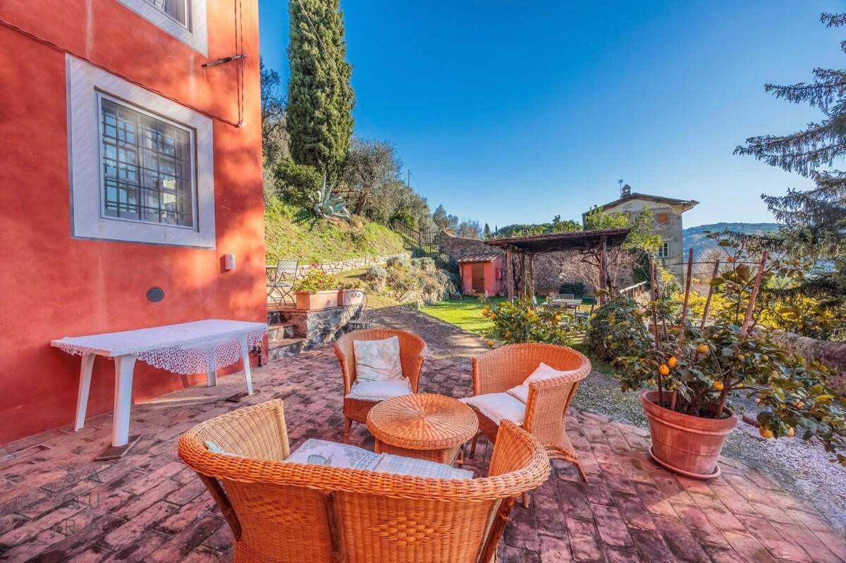 Gemütliche Terrasse mit Korbmöbeln und Ziegelboden, ideal für entspannte Stunden im Freien.