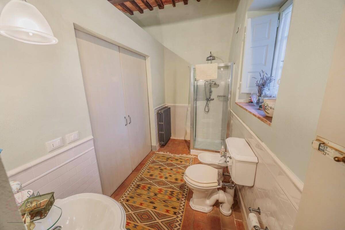 Funktionales Badezimmer mit Duschkabine, WC, Bidet und Terrakottaboden.