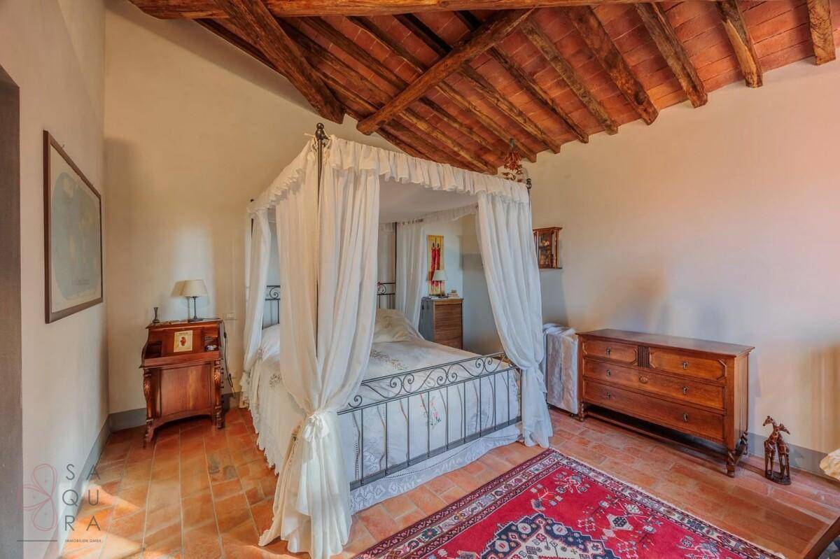 Charmantes Schlafzimmer mit Himmelbett, Holzbalkendecke und rustikalem Terrakottaboden.