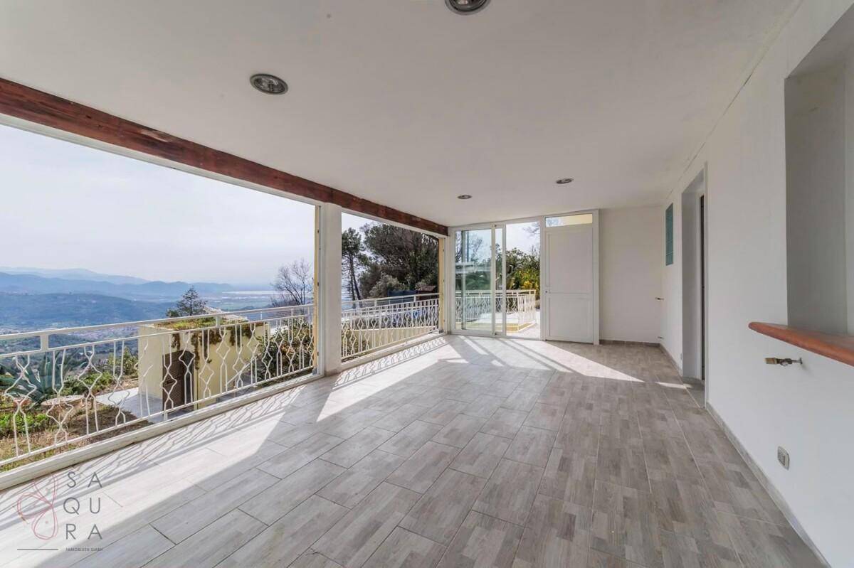 Helle Loggia mit weitem Panoramablick über die Landschaft und großen Fensterfronten.
