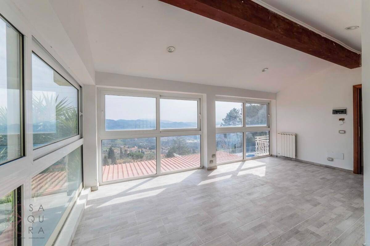 Heller Wohnraum mit weitem Ausblick, großen Fenstern und sichtbaren Holzbalken.